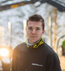 gutt i skog står foran skogsmaskin